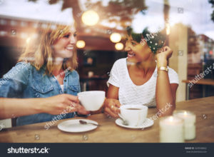 stock photo two multi ethnic friends enjoying coffee together in a coffee shop viewed through glass with 324558662